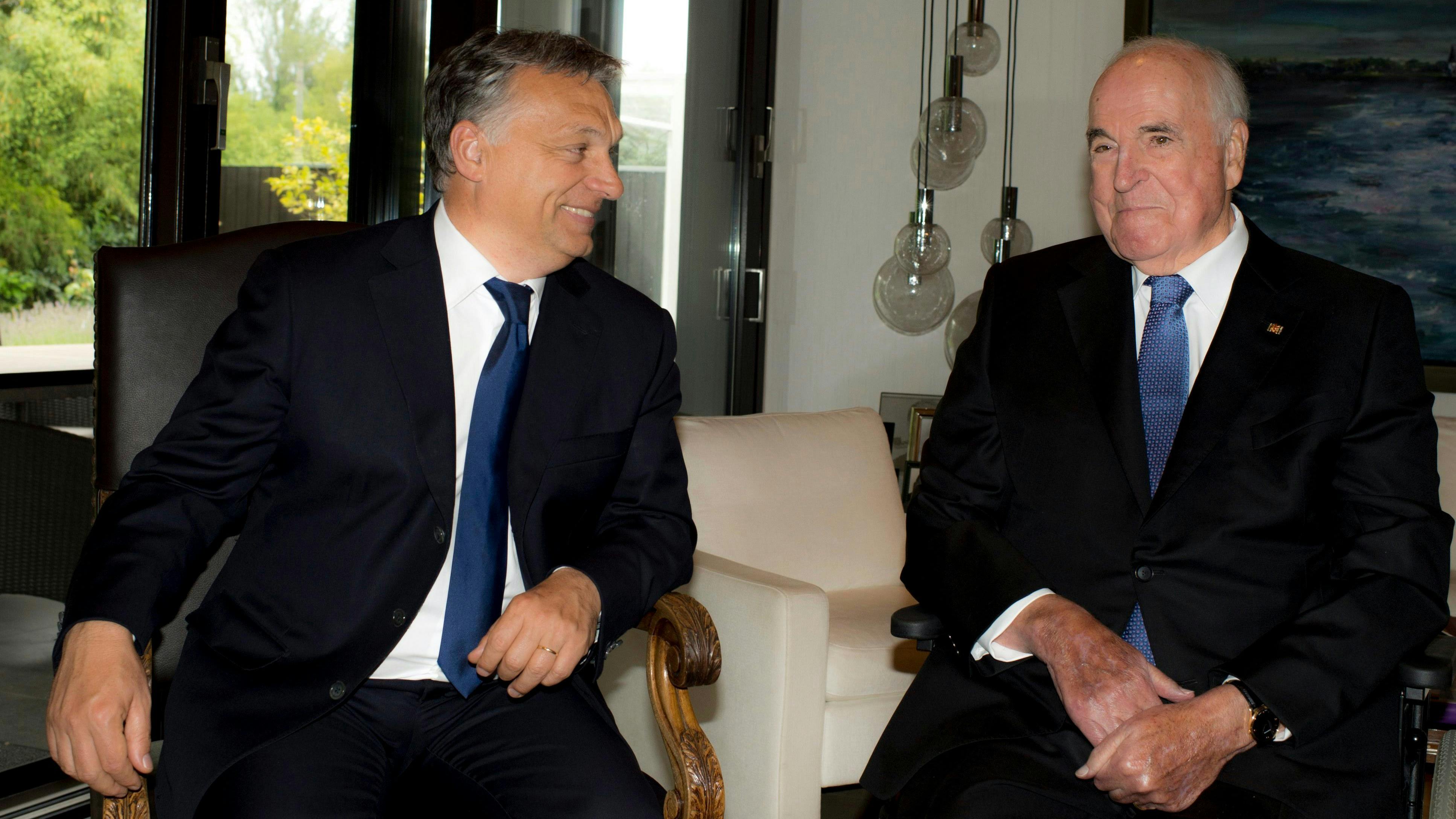 Wir sehen Victor Orban und Helmut Kohl nebeneinander sitzen, Orban ist Kohl zugewandt und lächelt ihn an. 