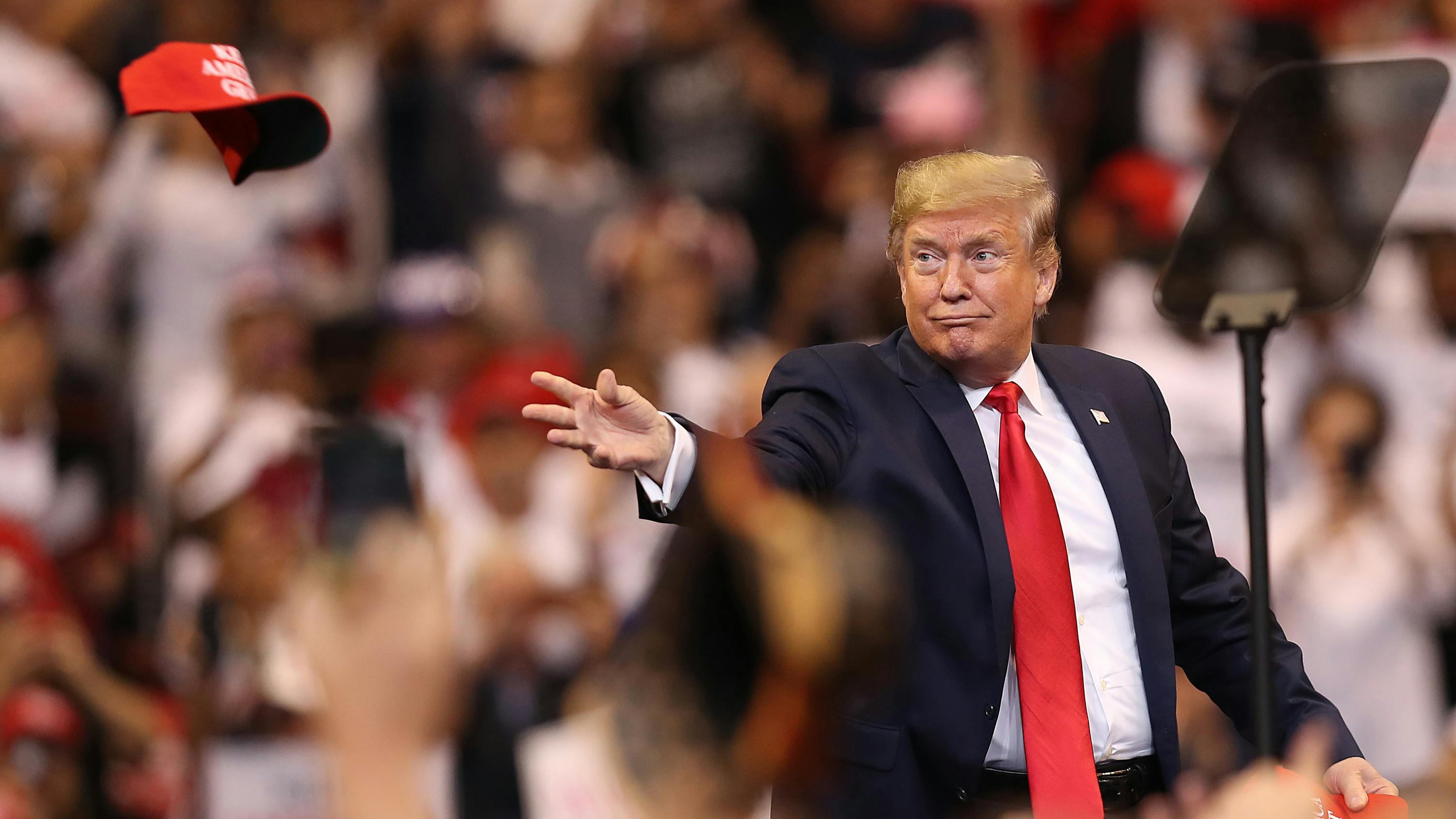 Wir sehen einen gut gelaunten Trump auf einer Wahlveranstaltung – und er wirft eine rote „MAGA“-Kappe in die Menge. 