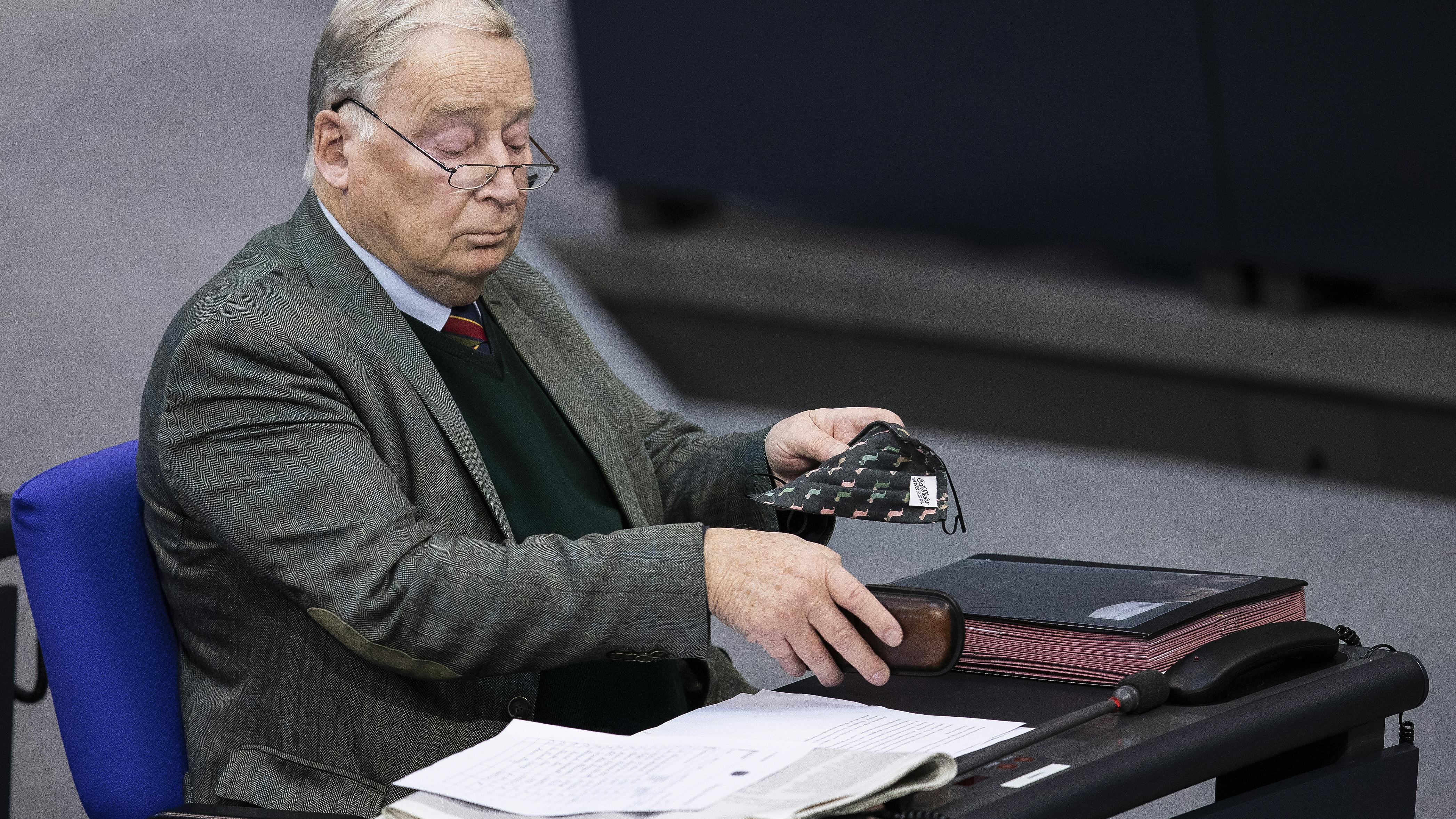 Der Vorsitzende der AfD, Alexander Gauland, sitzt während einer Debatte über das Corona-Virus im Bundestag auf seinem Platz und hat eine Maske in der Hand.