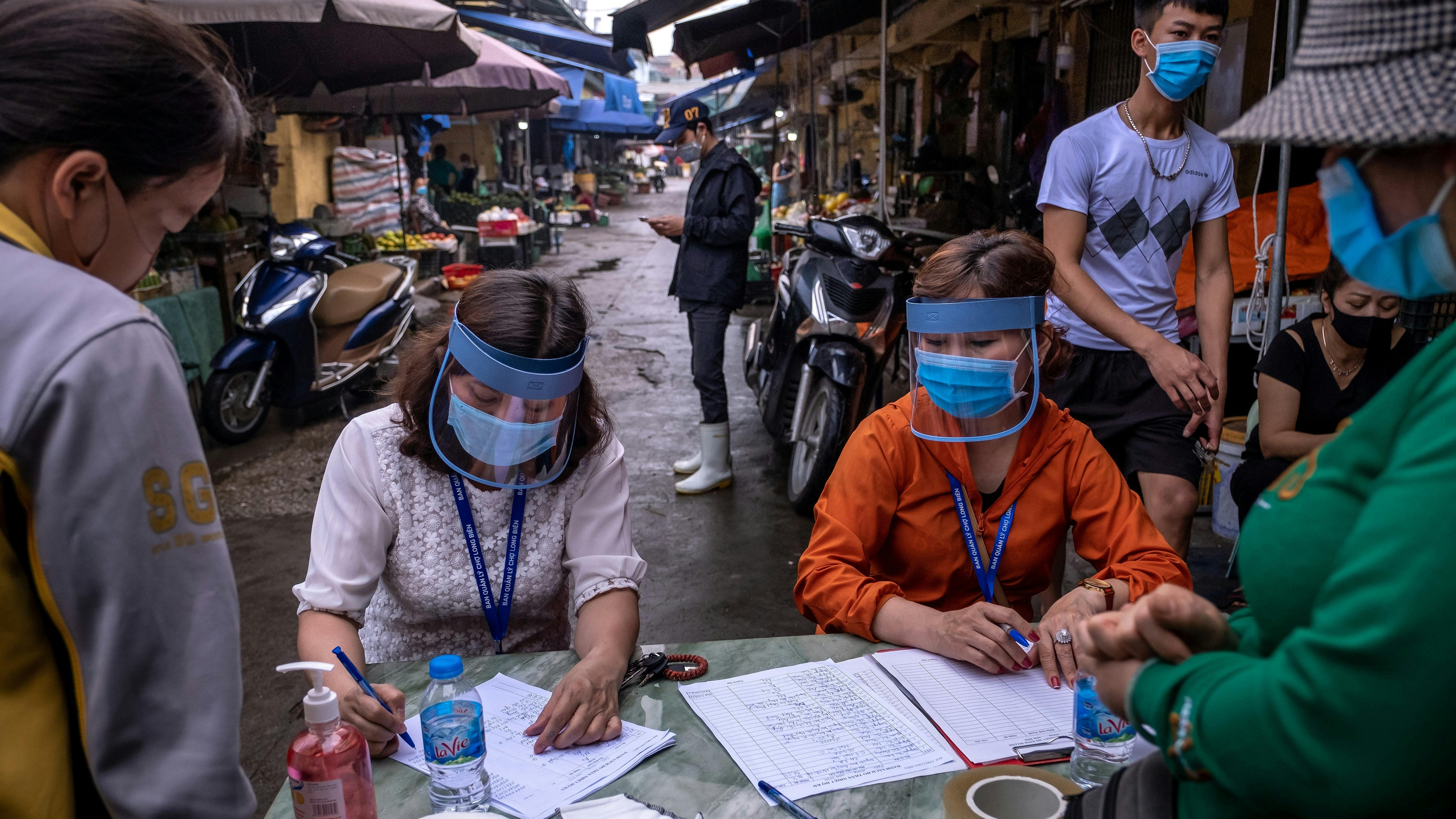 Marktpersonal trägt Gesichtsschutzschilde, während es am 18. April 2020 in Hanoi, Vietnam, auf dem Long Bien Markt für den Schnelltest auf Coronavirus-Krankheit (COVID-19) Informationen von Verkäufern und Arbeitern entgegennimmt. 