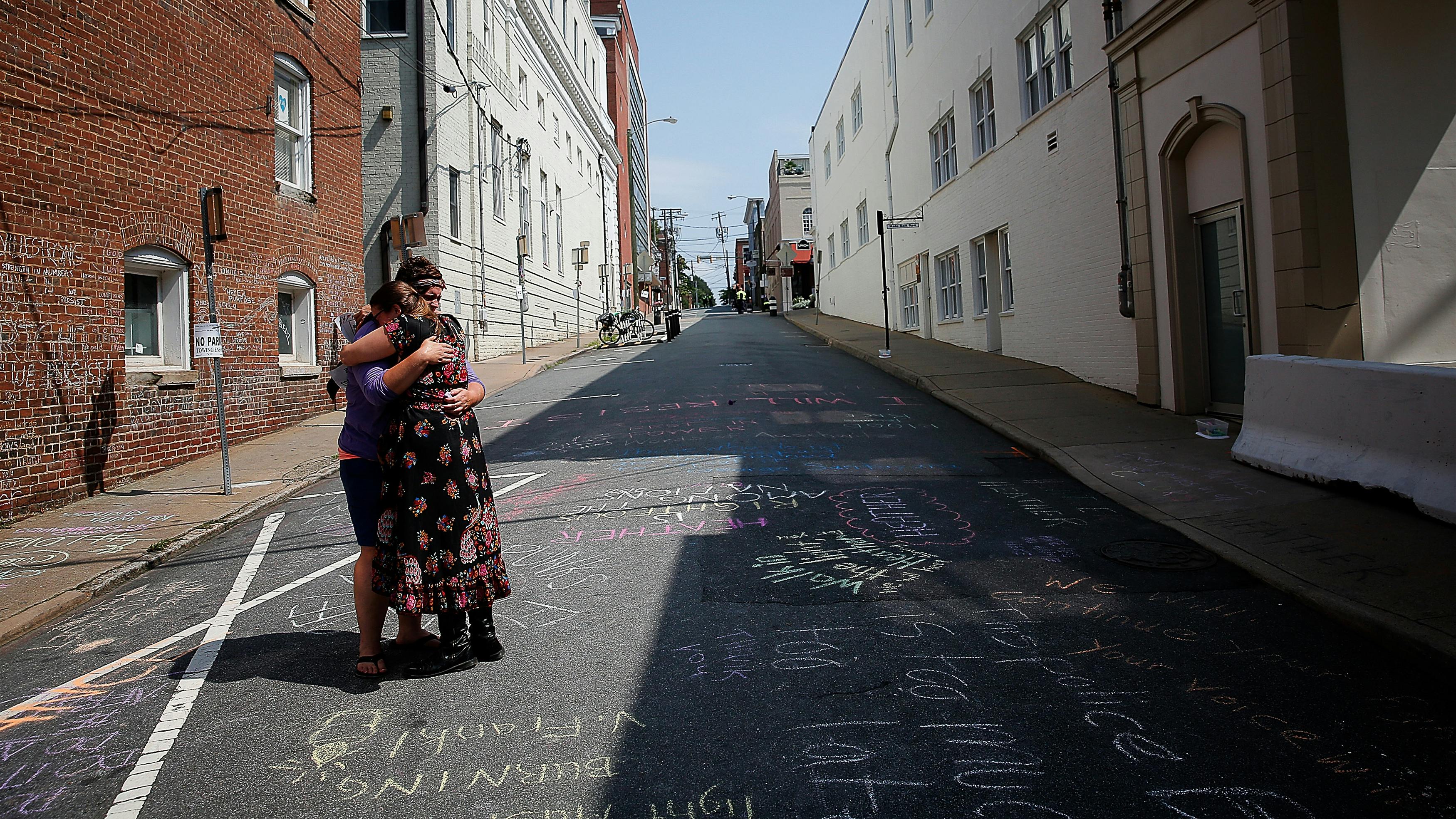 Jenn Franklin (L) und Gretchen Burgess (R), die bei den tödlichen Zusammenstößen in Charlottesville 2017 dabei waren, umarmen sich in der Nähe einer behelfsmäßigen Gedenkstätte für Heather Heyer, die bei einem Terroranschlag mit dem Auto getötet wurde.