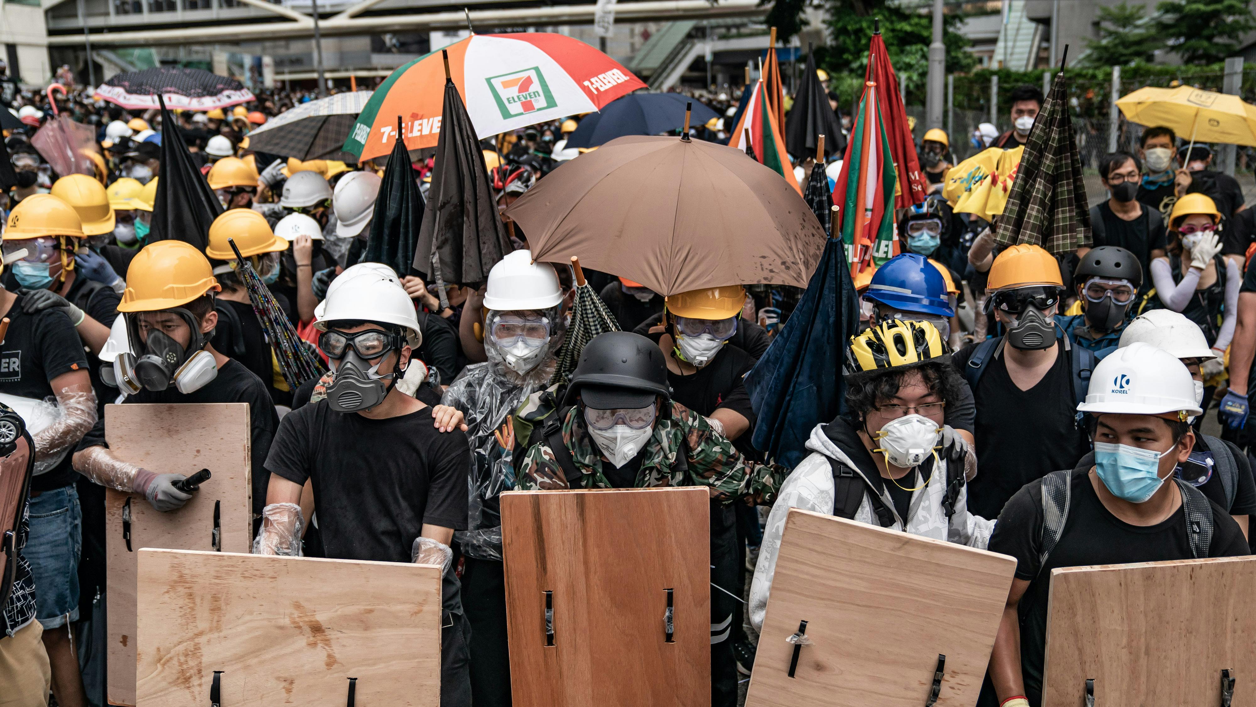 Demonstranten, die gegen das Auslieferungsgesetz protestieren, verteidigen sich mit einem behelfsmäßigen Schild und Schirmen während eines Zusammenstoßes mit der Polizei außerhalb des Legislativratskomplexes.