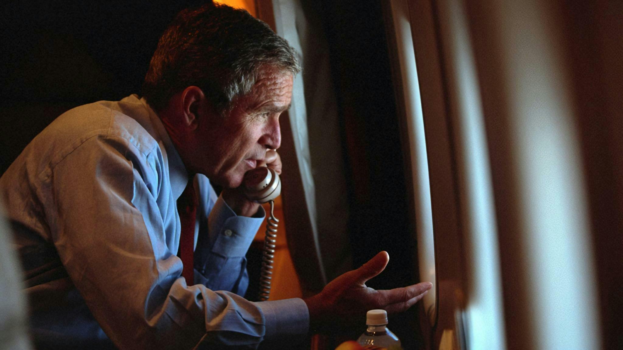 Innenansicht; Präsident George W. Bush schaut aus einem Flugzeugfenster, Telefonhörer am Ohr.