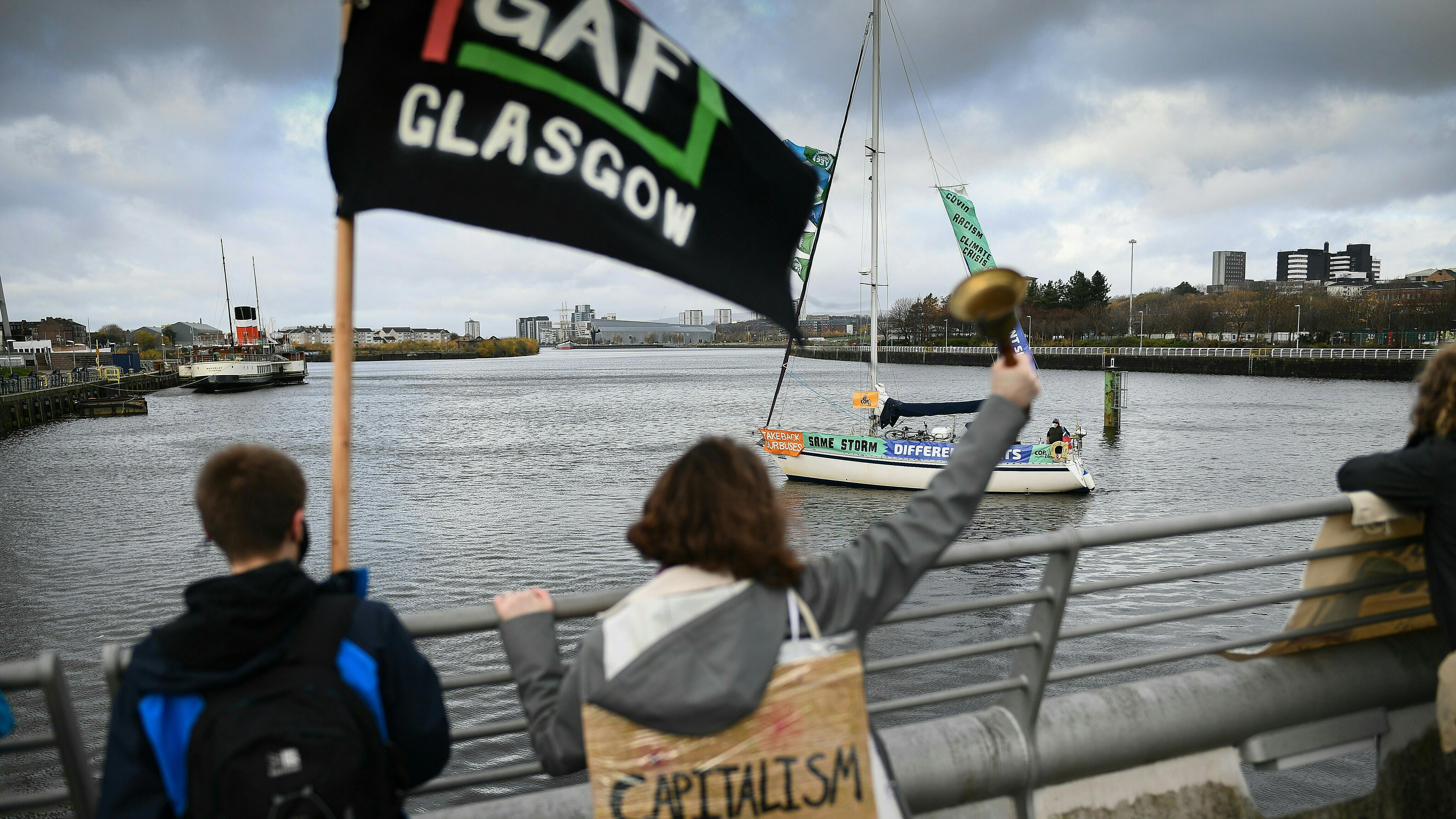 Protestierende schwenken Fahnen im Hafen von Glasgow.