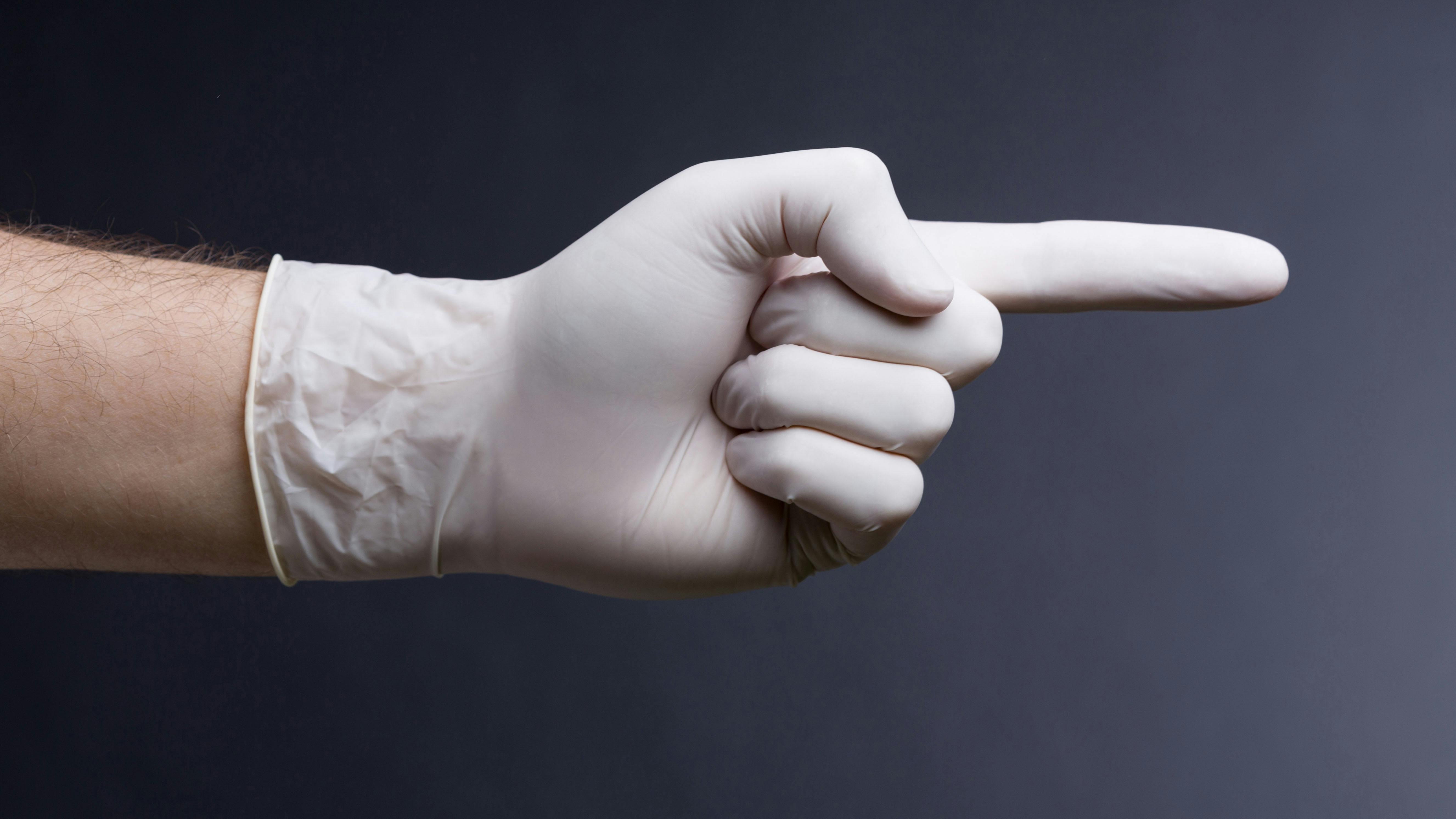 Eine Hand mit medzinischem Handschuh, leicht nach oben gebogen, in der Haltung für eine Prostata Untersuchung.