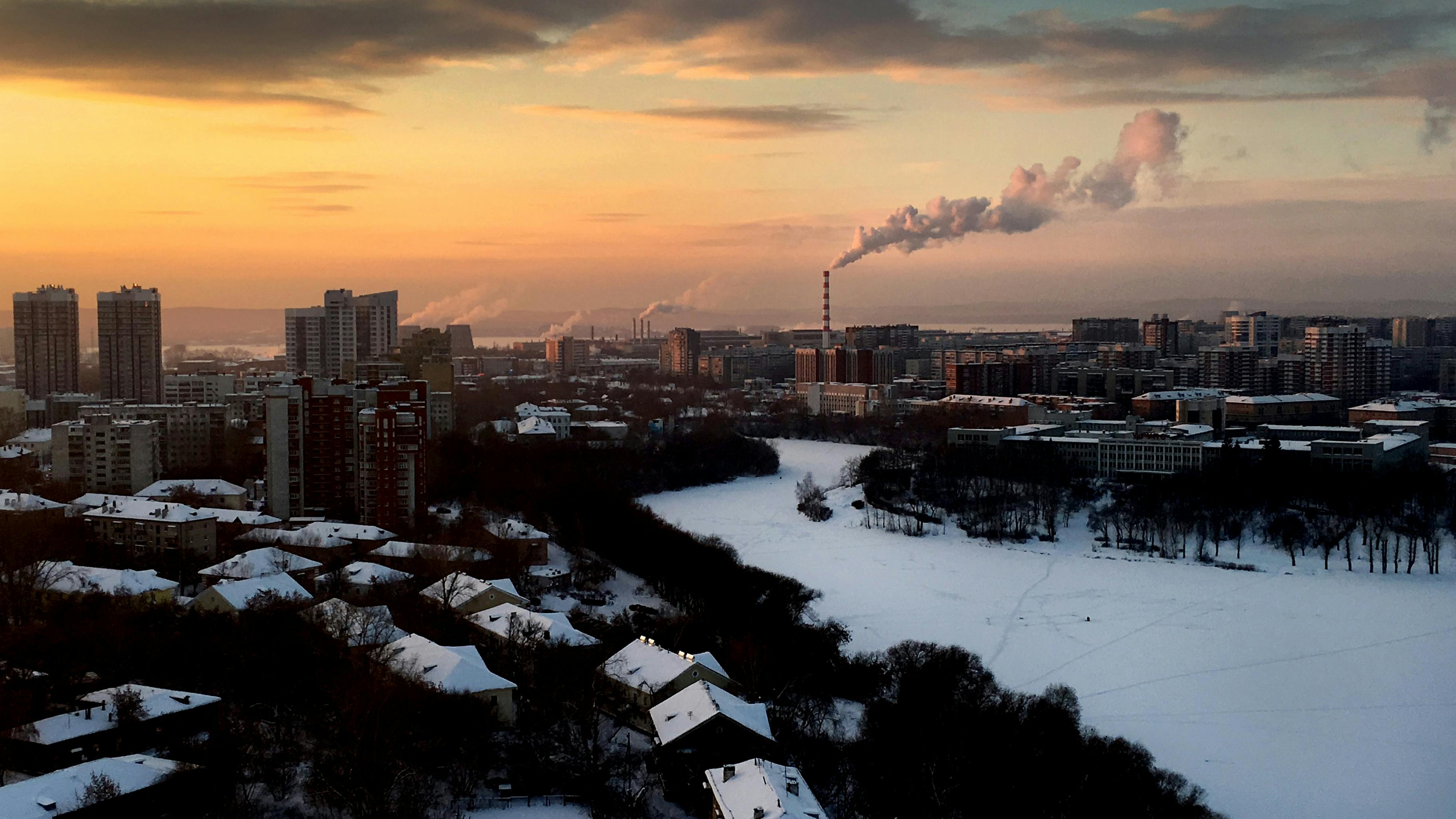 Jekaterinburg- Eine verschneite Urbane Landschaft mit zugefohrenem Fluss und rauchendem Schornstein.