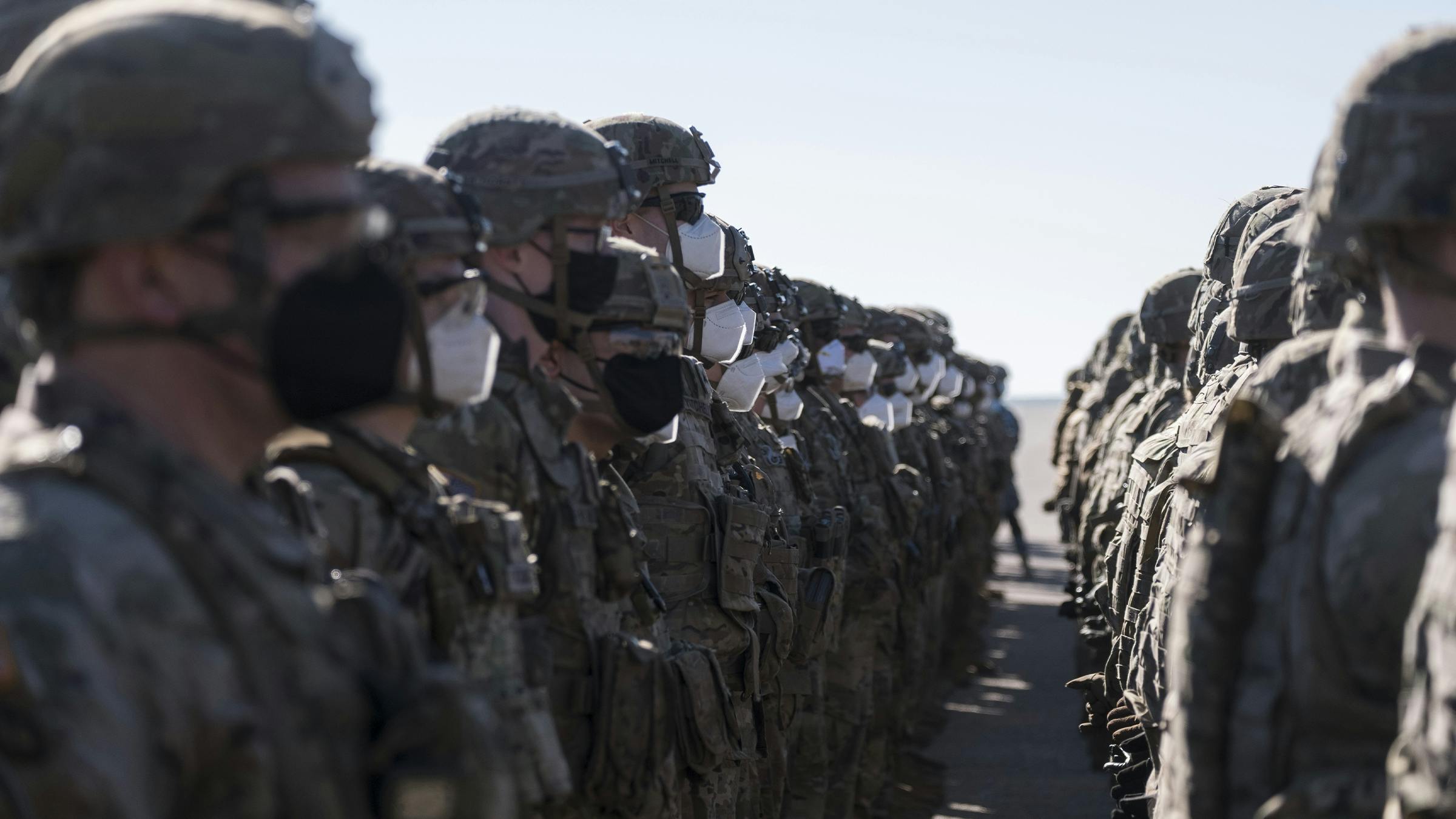 Soldaten stehen in Reih und Glied. Viele tragen eine Atemschutzmaske.