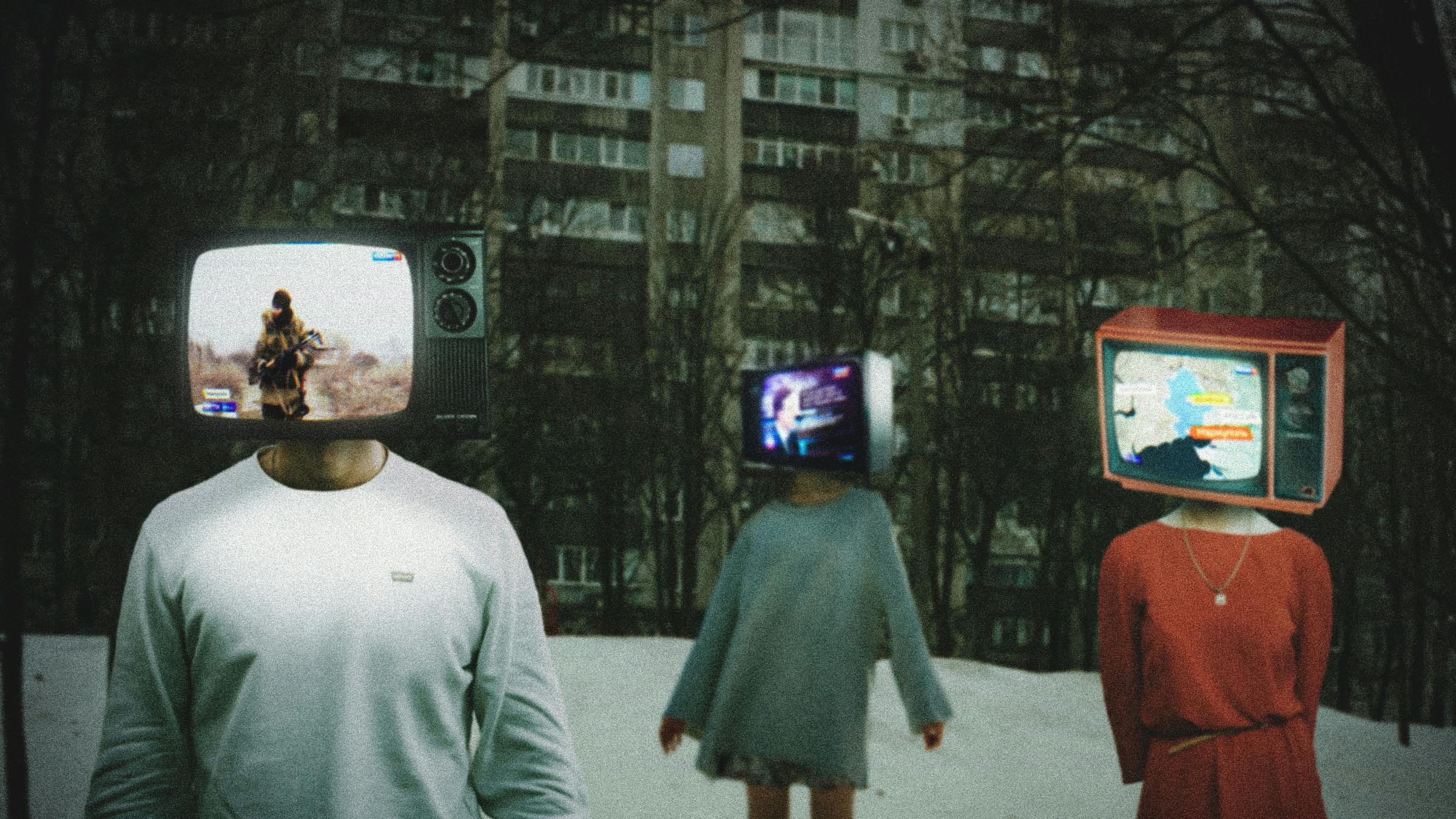 Surreale Fotomontage: 3 Menschen stehen vor einem sovietischen Plattenbau. Statt ihren Köpfen tragen sie Fernseher auf den Schultern, in denen Szenen aus russischem Staatsfernsehen zu sehen sind. 