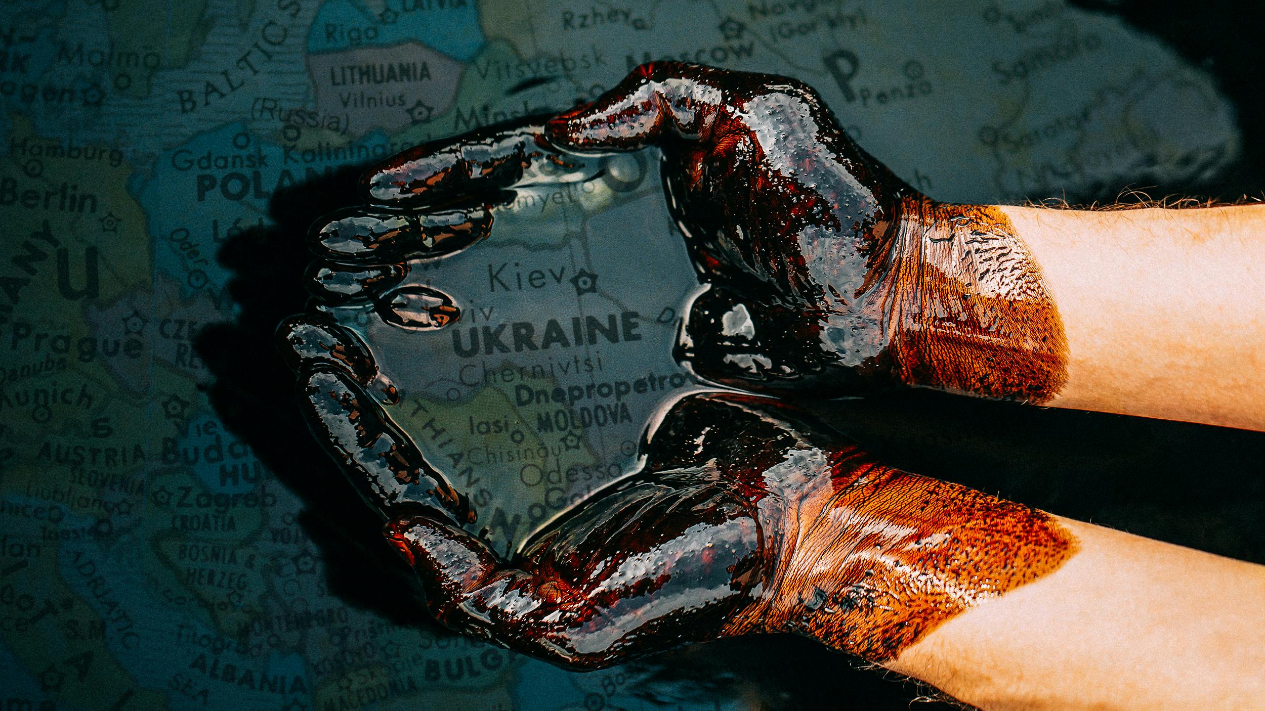 Hände schöpfen Öl aus einer Lache. darunter liegt eine Karte von Europa.