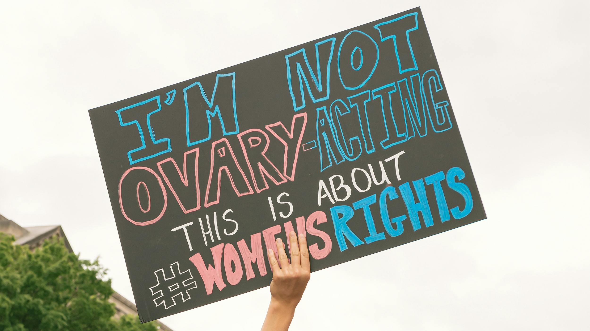 Auf einer Demonstration wird ein Schild hochgehalten. auf dem „Im not ovary-acting, this is about women's rights“ steht.