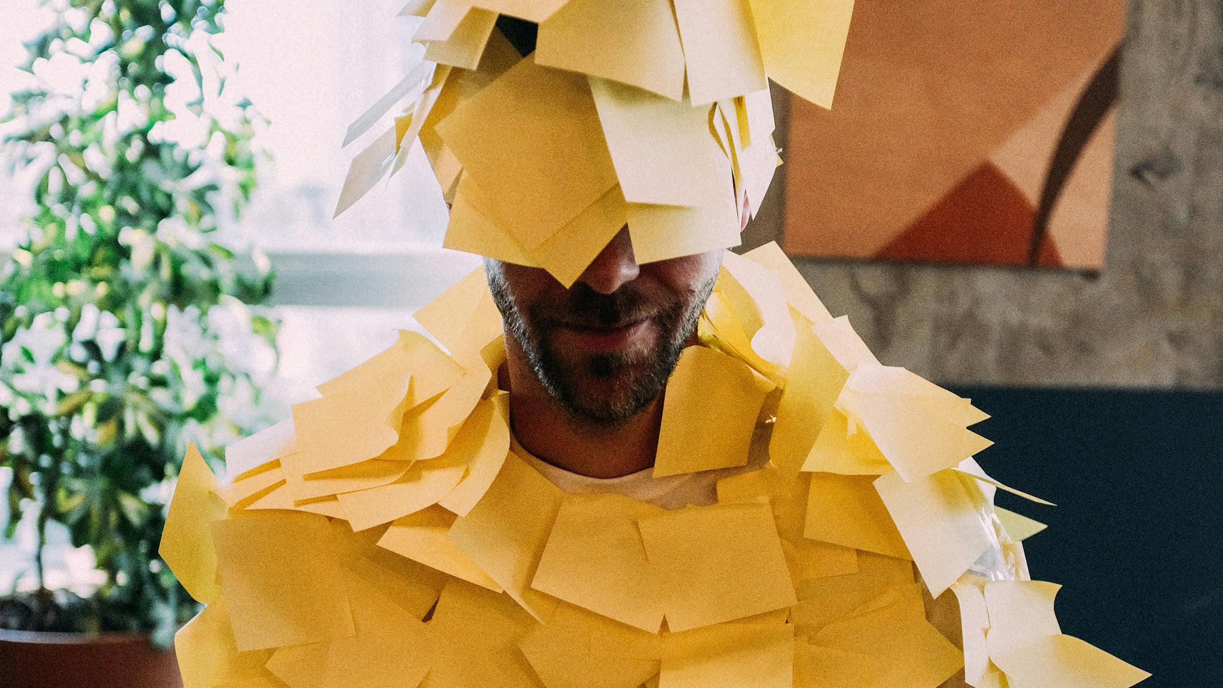 Ein Mann ist über und über mit Post-It-Zetteln beklebt.