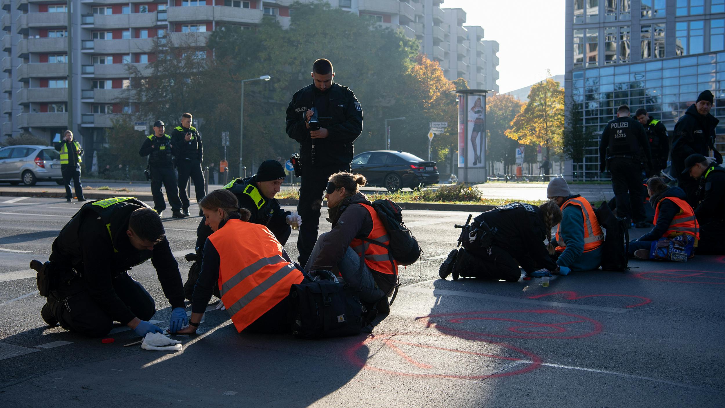 Man sieht eine Gruppe von Aktivist:innen, die sich auf einer Straße festgeklebt haben