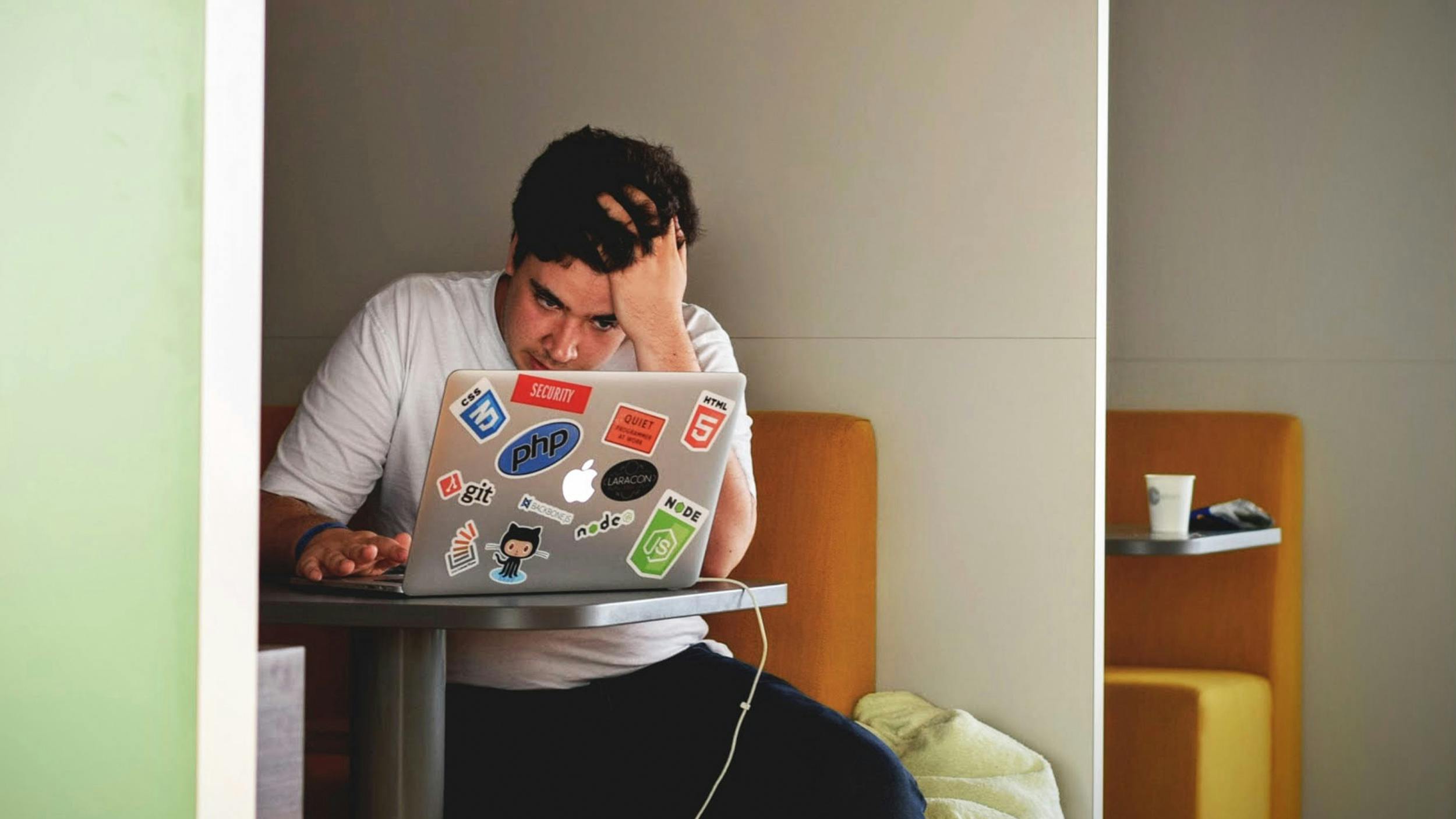 Ein Mann sitzt vor einem Laptop und greift sich verzweifelt ins Haar.