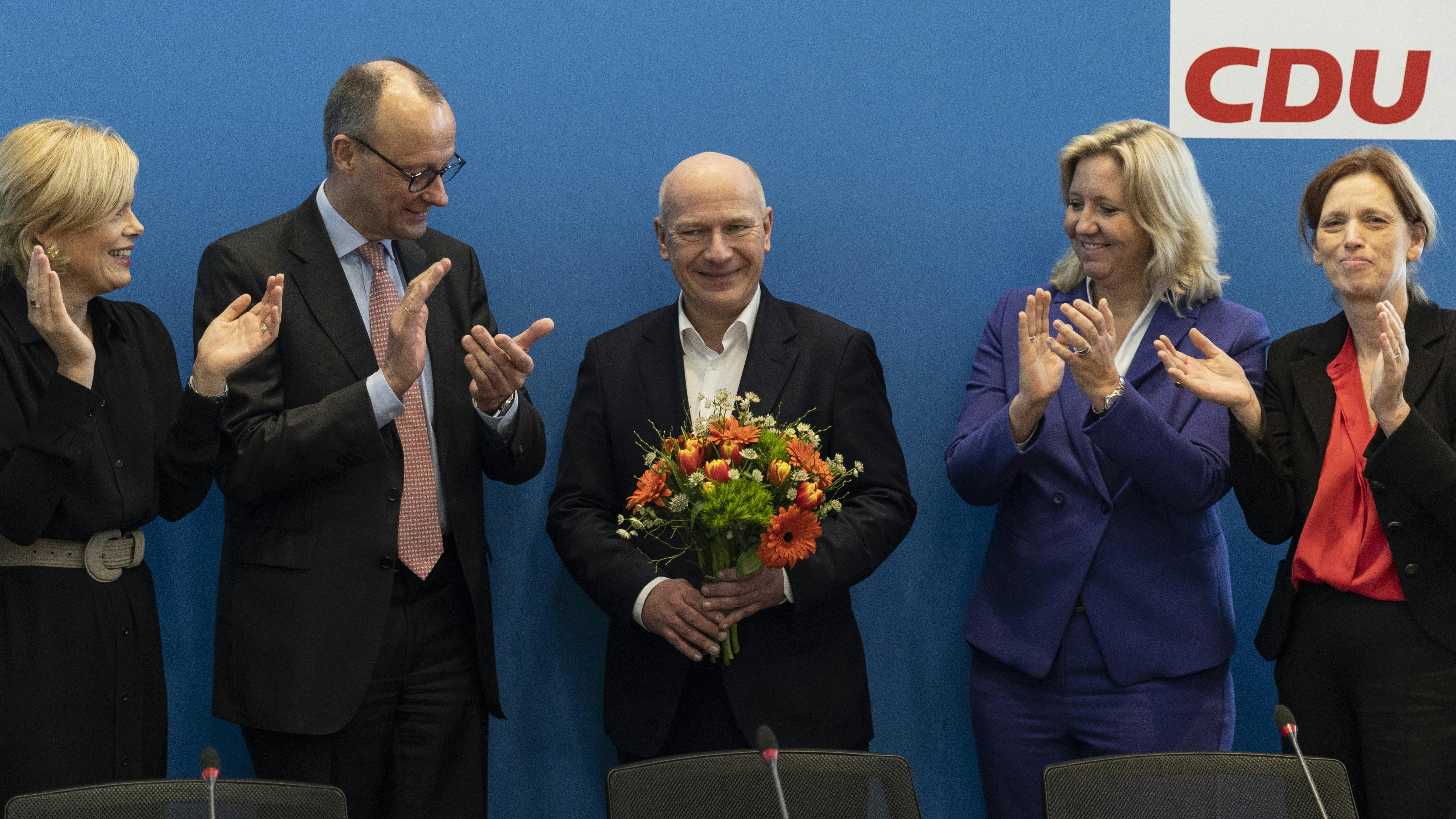 Kai Wegener und seine Partei-Gefährt:innen stehen beieinander. Er hält einen Blumenstrauß.