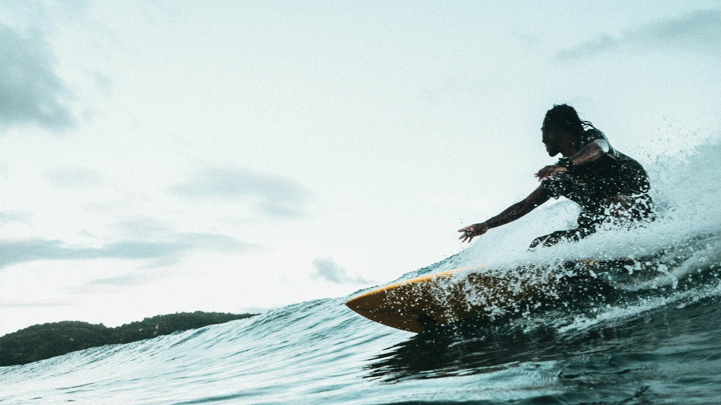 Eine Frau reitet auf einem Surfboard über eine Welle.