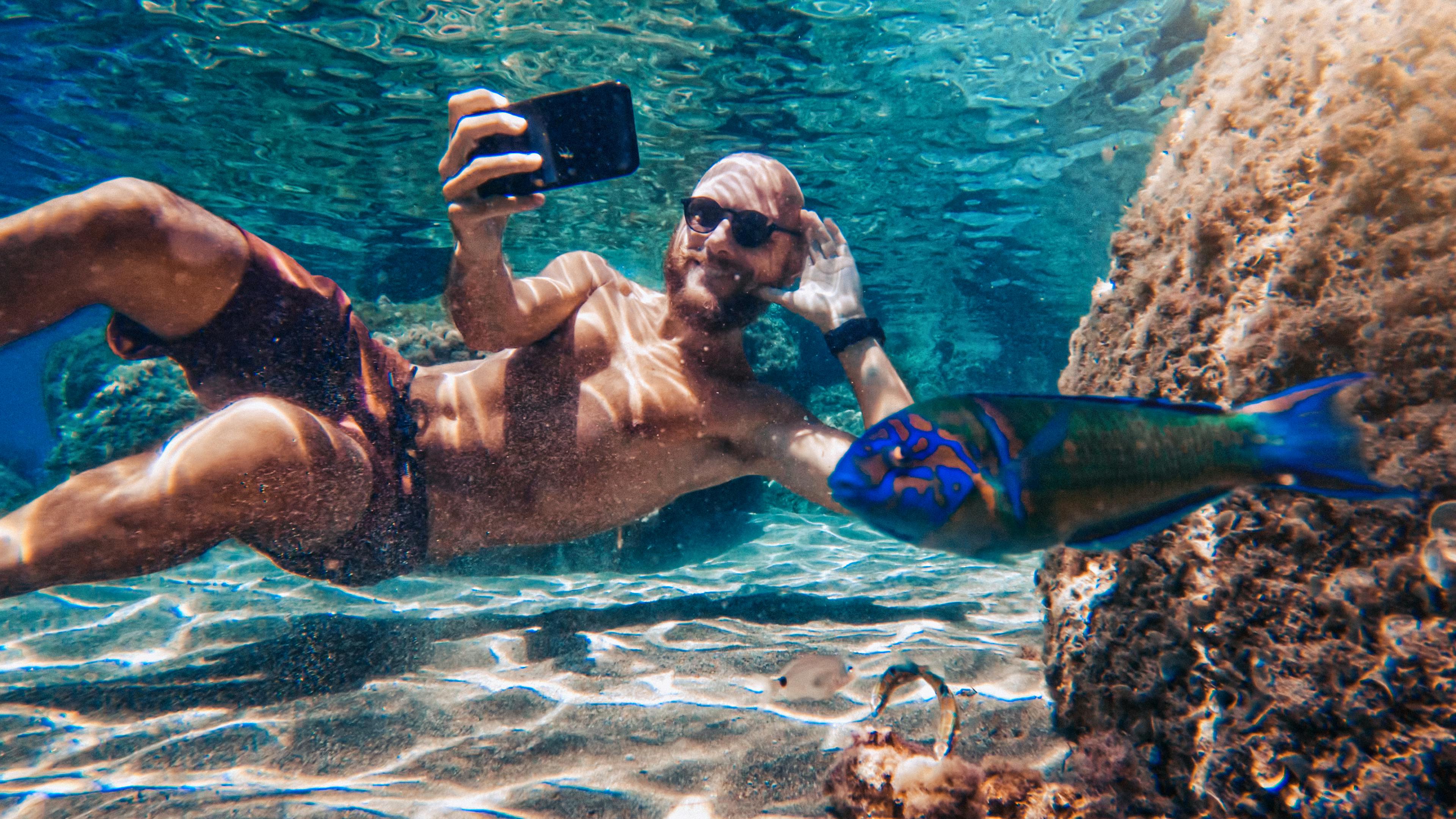 Ein Mann man ein Selfie beim Tauchen unter Wasser.