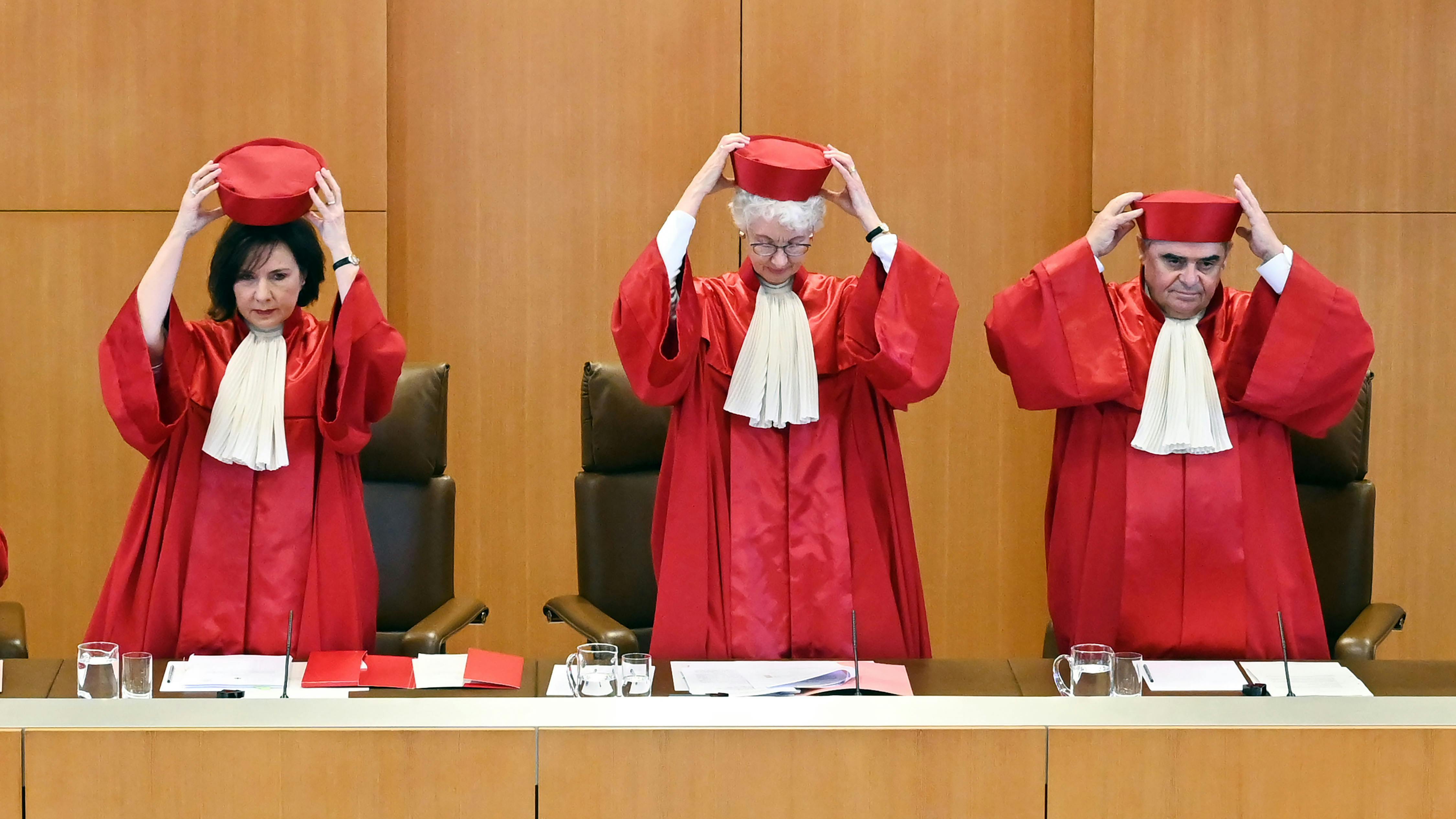 Das Bild zeigt drei Personen, die rote Roben und flache, rote Hüte tragen. Der Zweite Senat des Bundesverfassungsgerichts, (l-r) Sibylle Kessal-Wulf, Doris König (Vorsitzende) und Peter Müller, verkündet das Urteil in Sachen „Zweites Nachtragshaushaltsgesetz 2021“. 