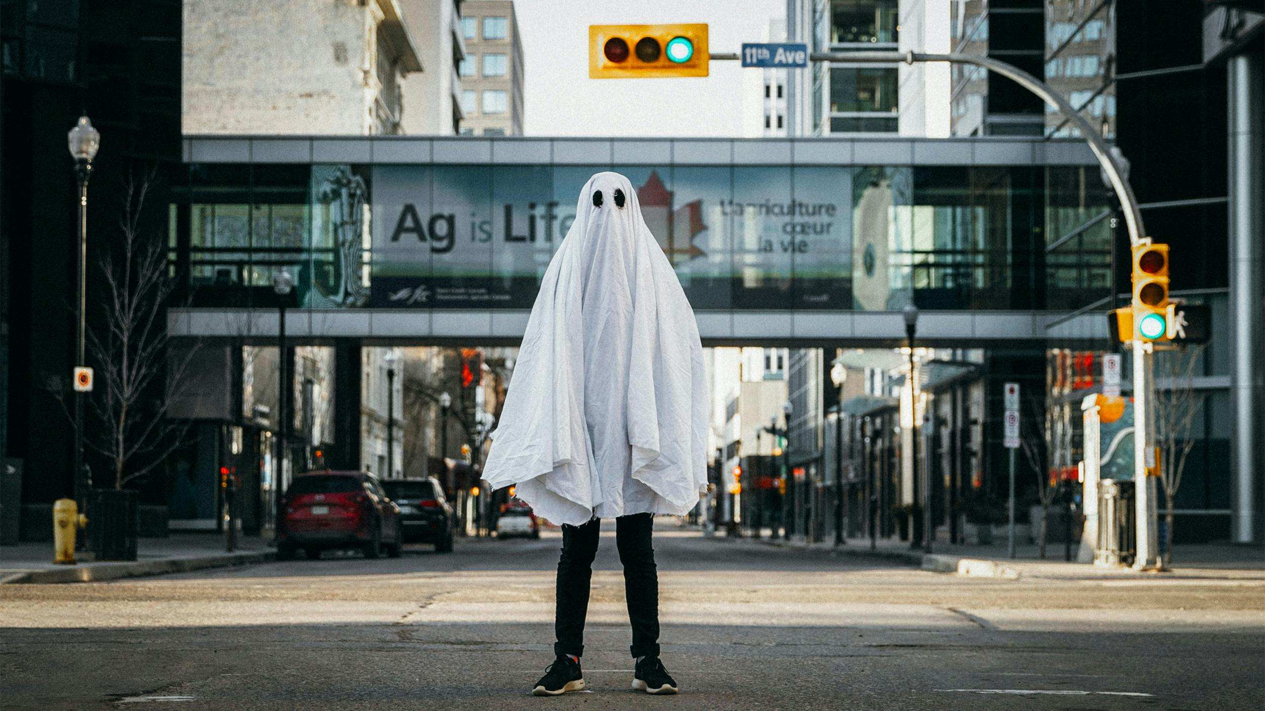 
Ein Mensch steht als Geist verkleidet auf einer Straßenkreuzung