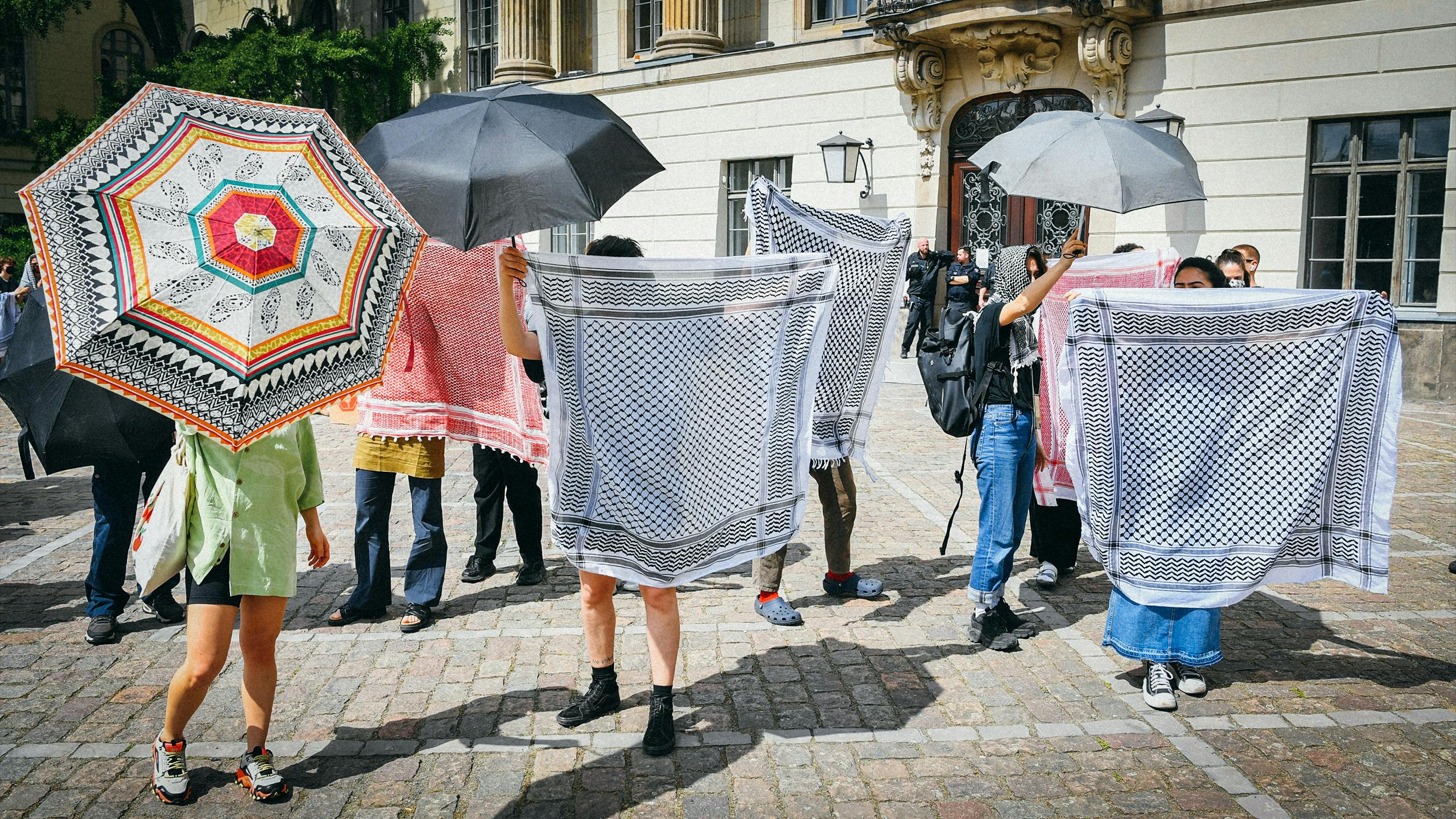 Eine Gruppe Menschen hält ihre traditionellen Tücher so in die Luft, dass sie nicht mehr zu erkennen sind. 