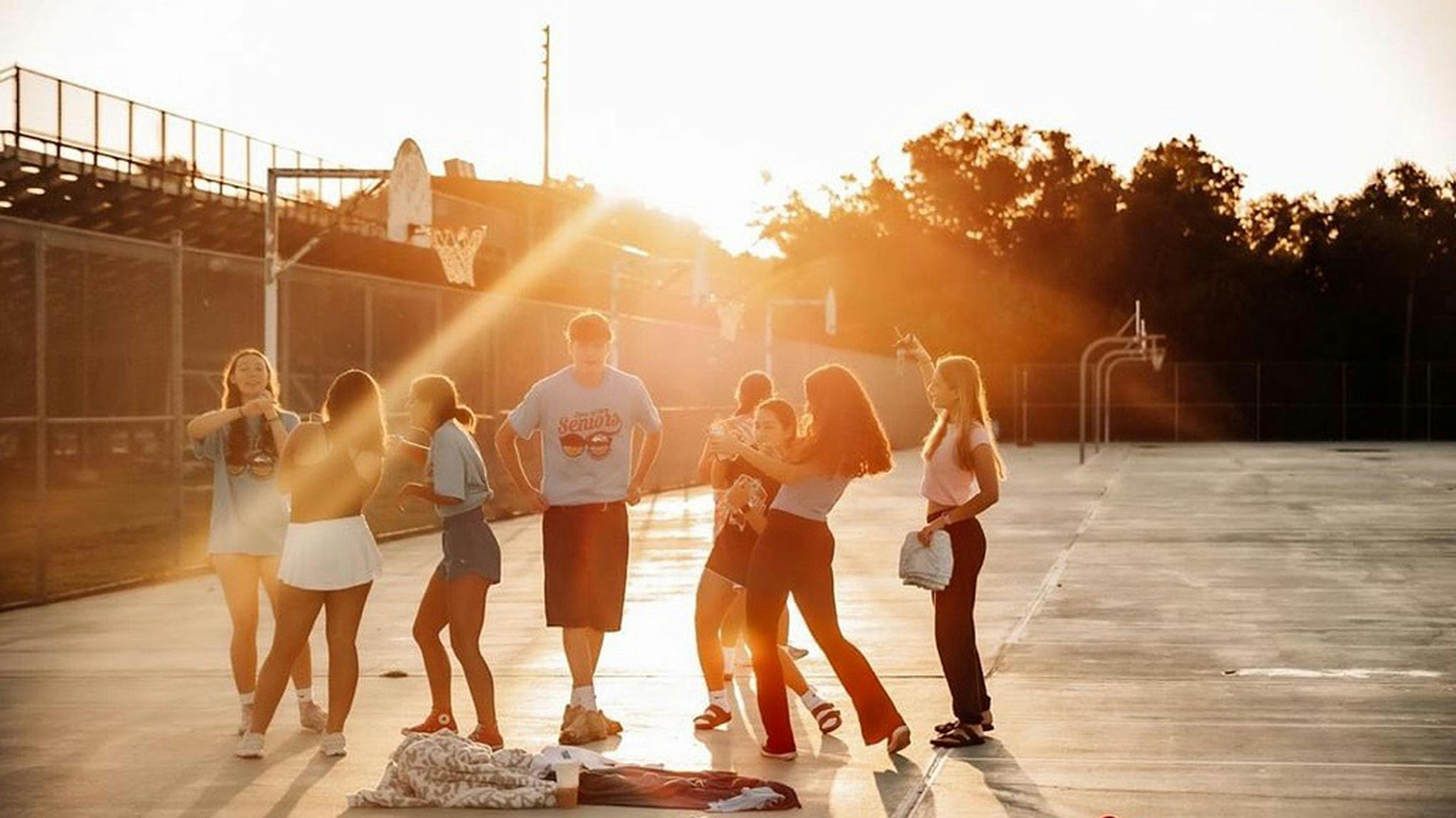 Eine Gruppe von Menschen steht auf einem Basketballplatz bei Sonnenaufgang  