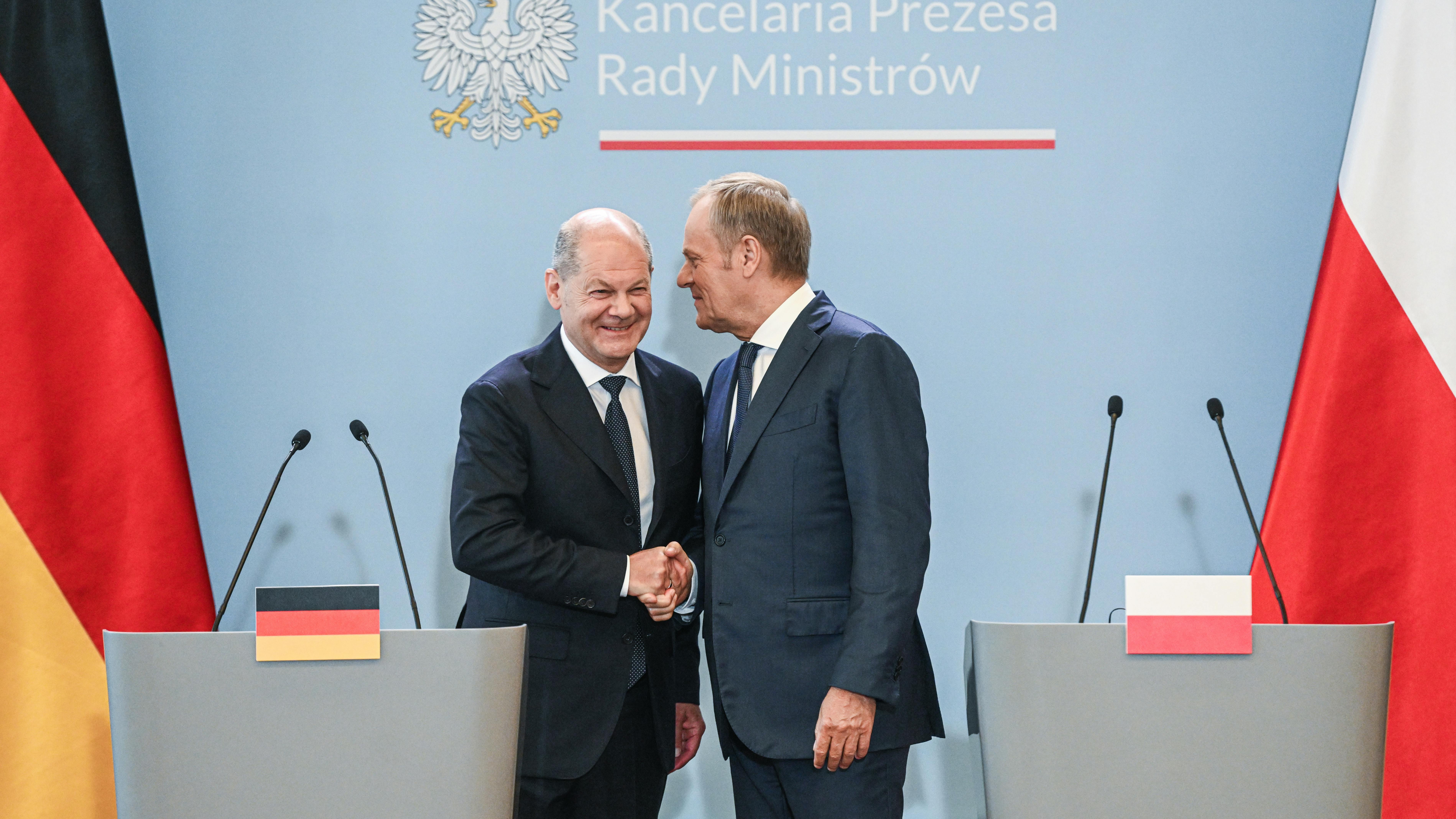 Olaf Scholz und Donald Tusk schütteln sich lächelnd die Hand.