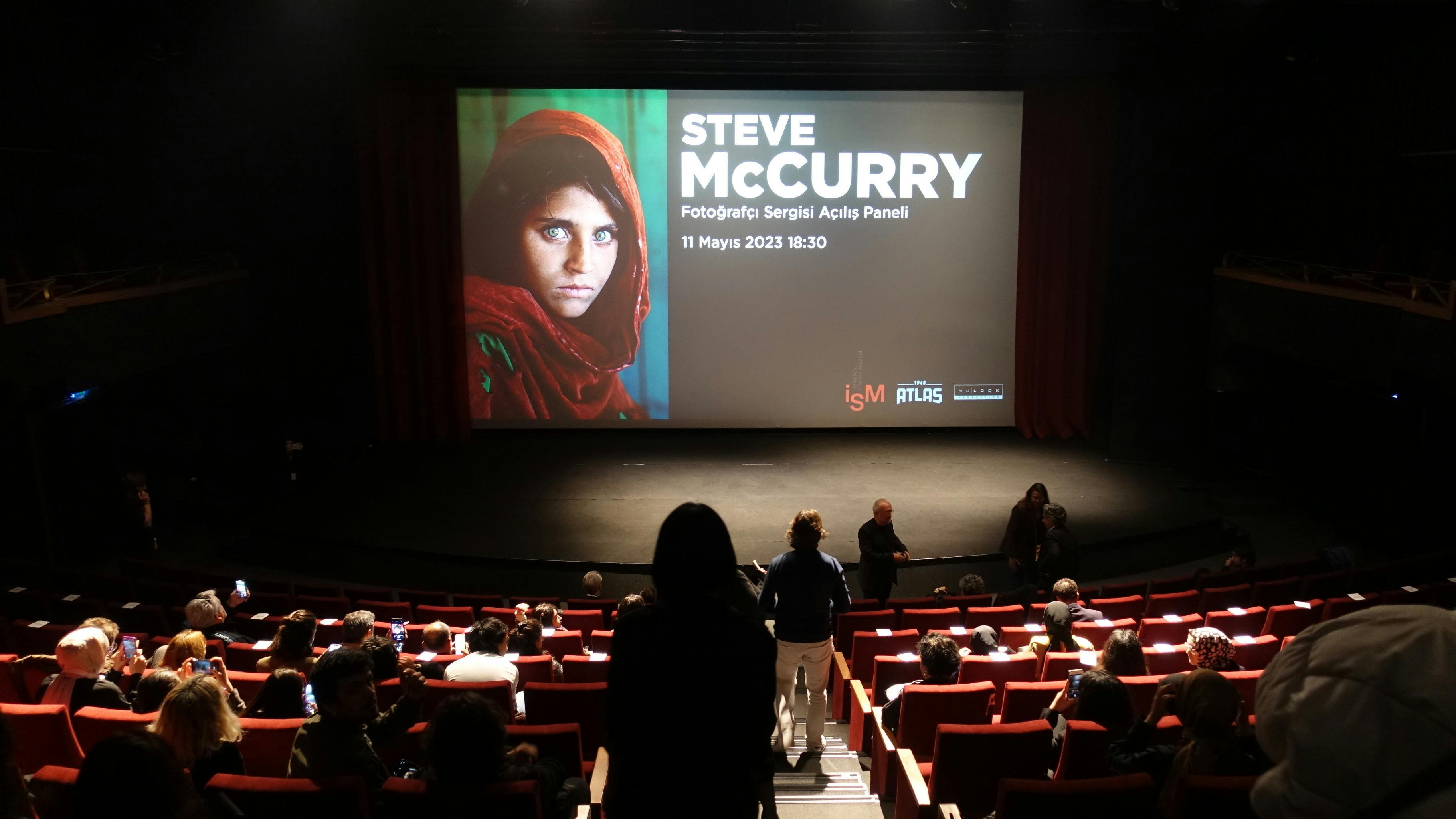 Auf einem großen Bildschirm ist das Foto von Sharbat Gula zu sehen, daneben steht in gr0en Buchstaben „Steve McCurry“. 