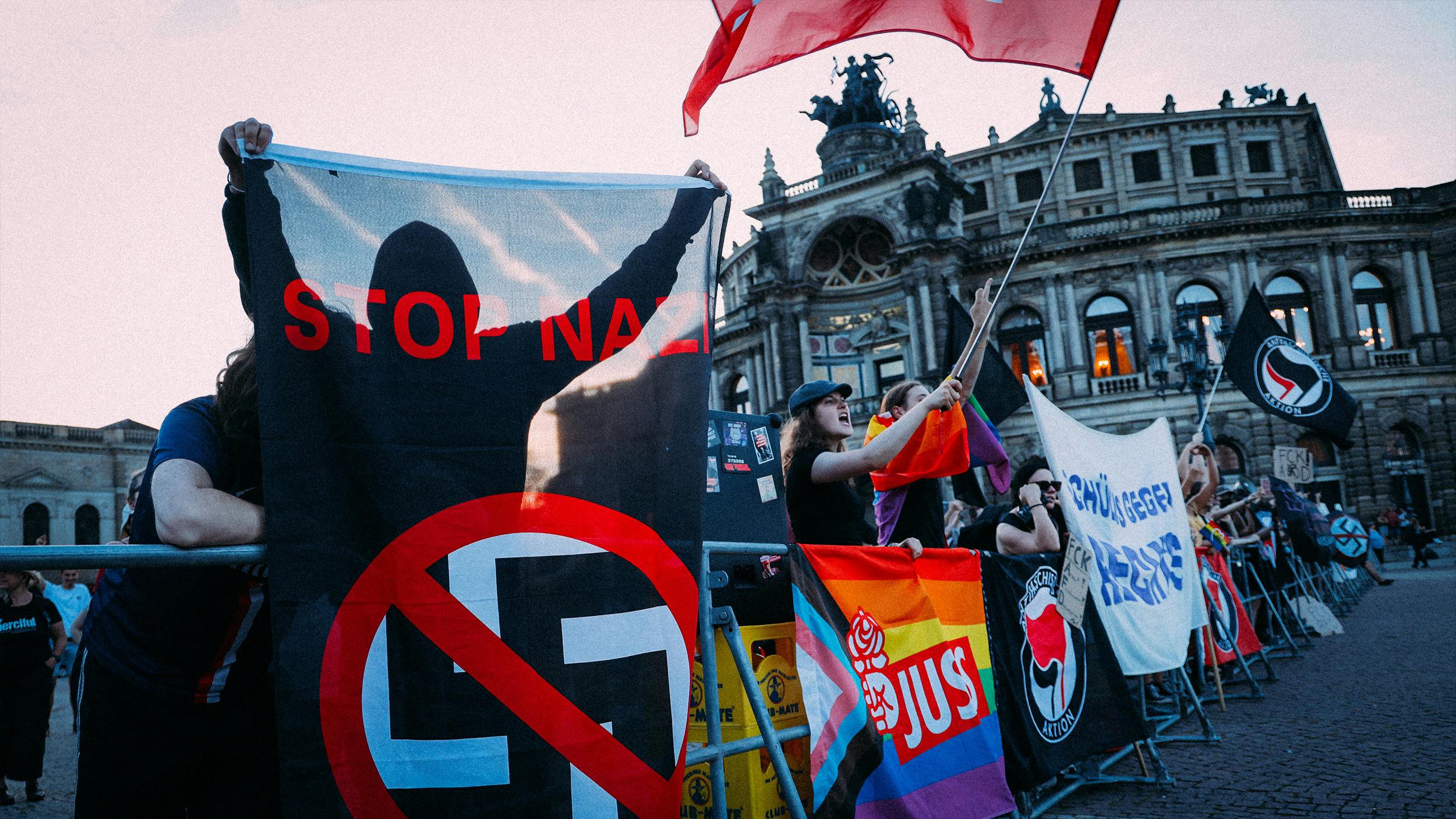 Menschen demonstrieren in Dresden gegen die AfD, sie halten Plakate in die Höhe. Im Hintergrund sieht man die Semperoper.