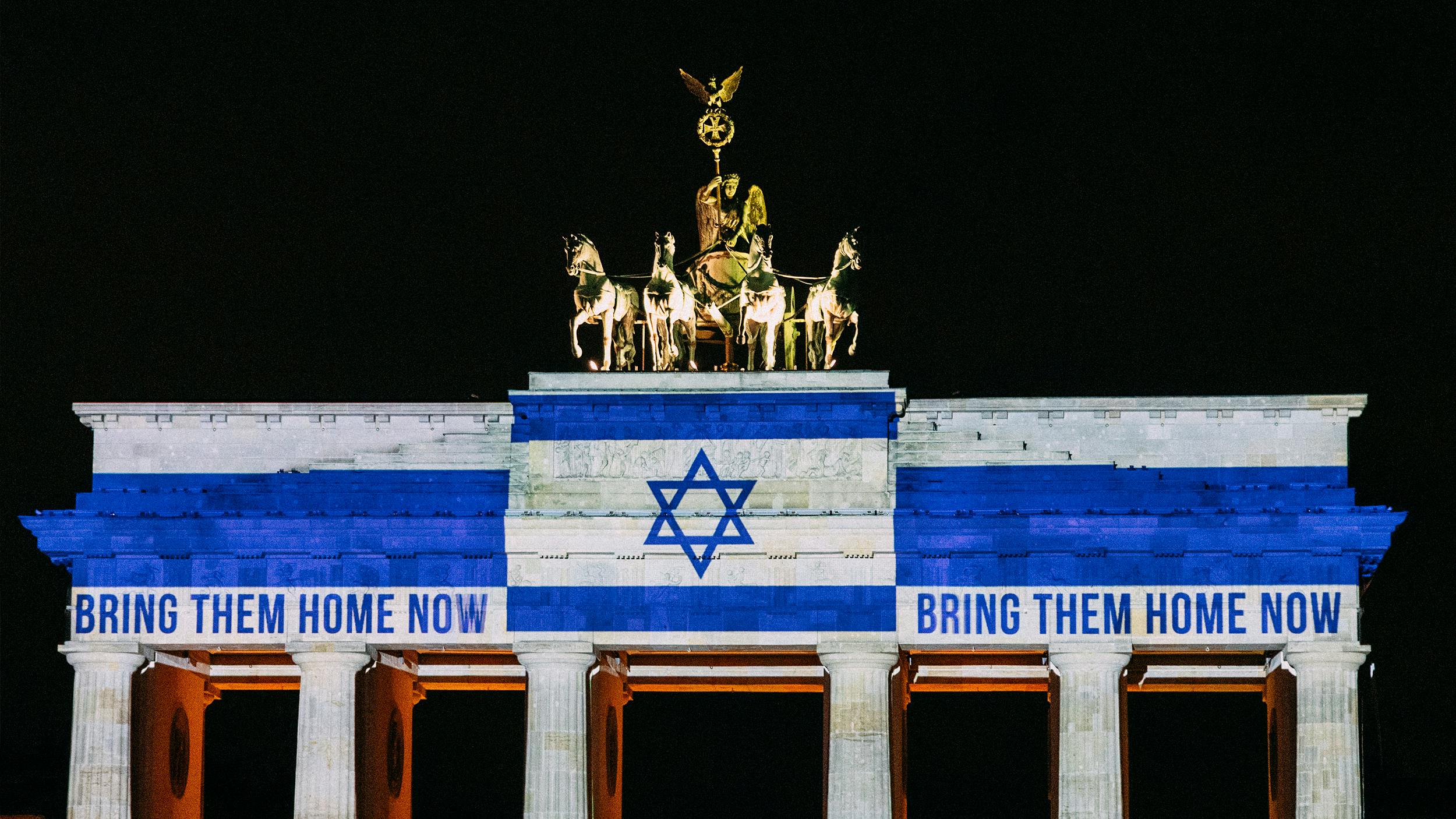 Das Brandenburger Tor, darauf ist eine israelische Fahne projeziert und es sind die Worte „Bring them home now“ zu lesen.