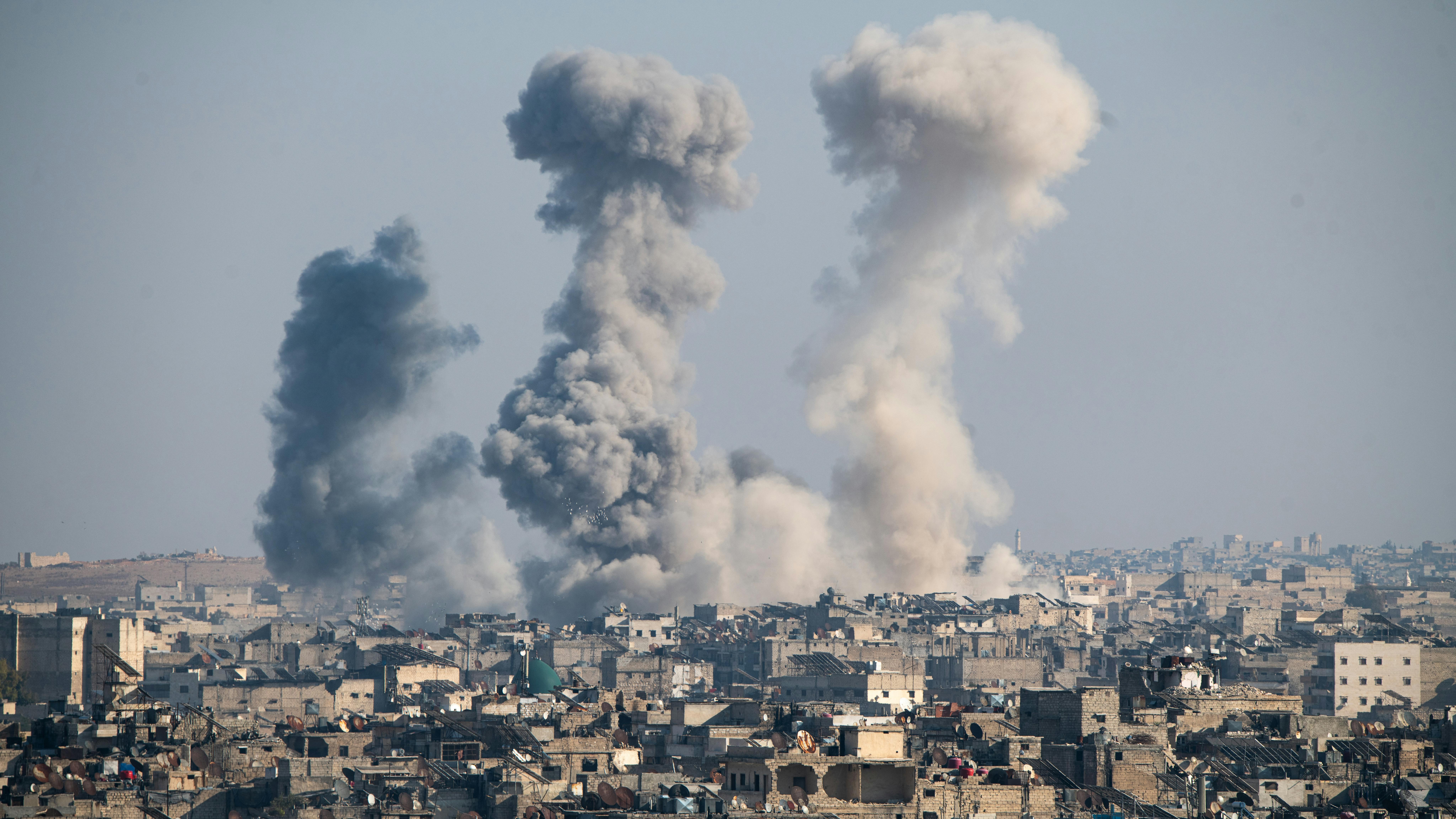 Über der Stadt Aleppo steigen drei Rauchsäulen auf.